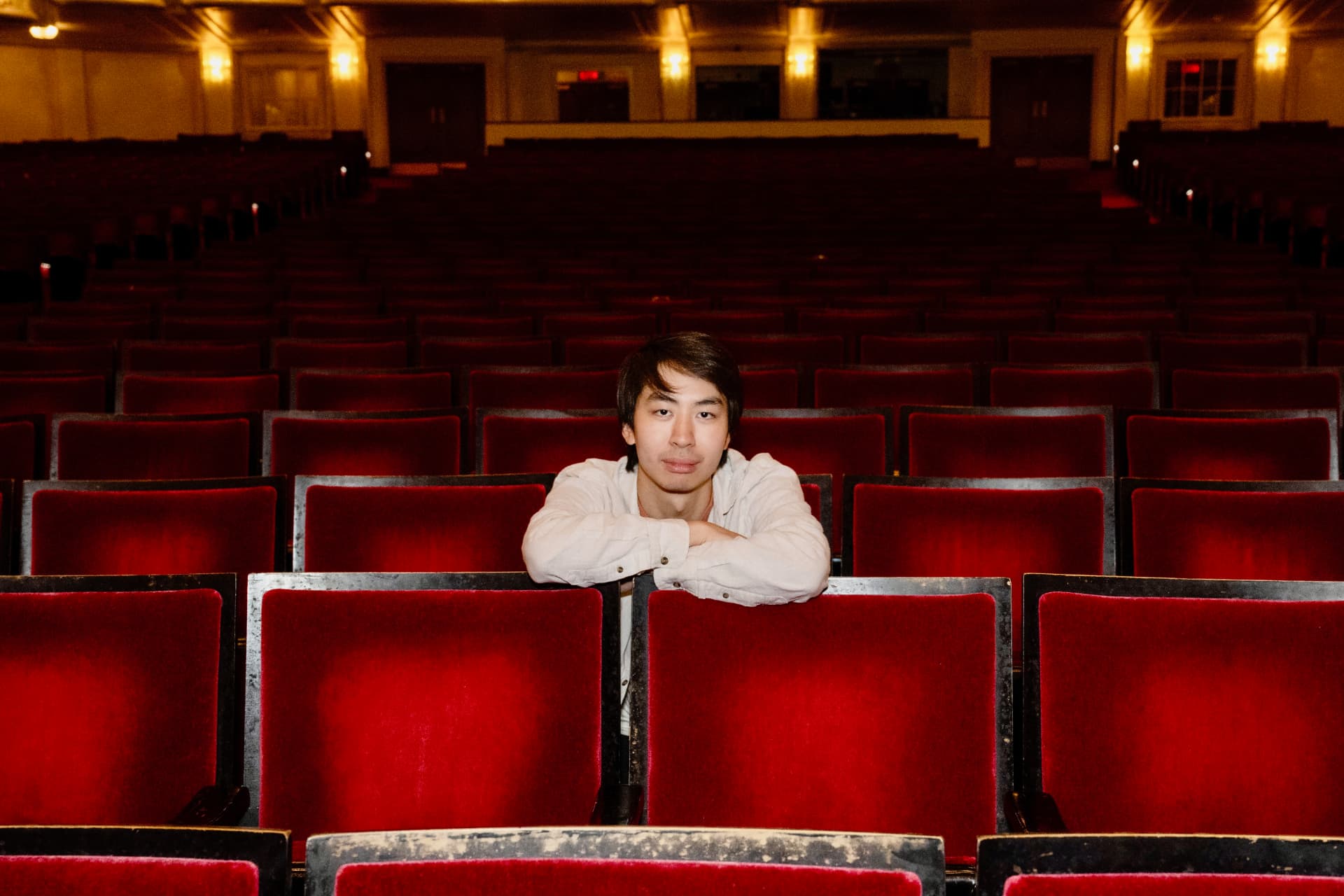 Ian Tam seated in an empty concert hall